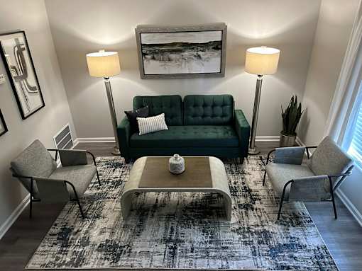 A living room with a green couch, two chairs, a coffee table, and a rug.