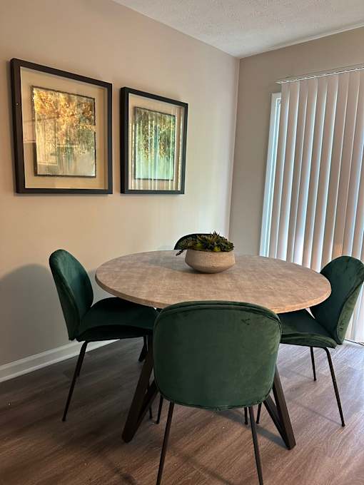 A dining table with four chairs and two pictures on the wall.