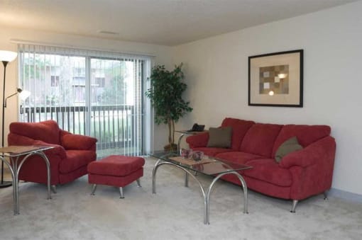 a living room with a red couch and chair and a sliding glass door