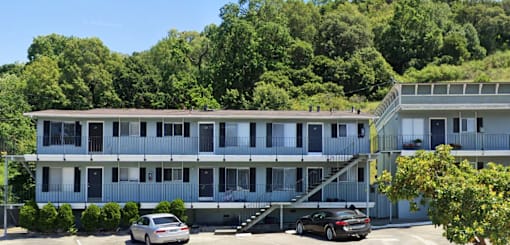 A car is parked in front of a two-story apartment building.