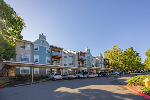 A row of townhouses with cars parked in front.