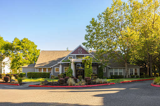 A building with a red X on the roof is surrounded by trees and bushes.
