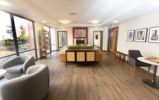 A living room with a grey sofa, a wooden coffee table, and a chess board on the table.