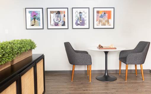 A dining table with four chairs and three pictures on the wall.