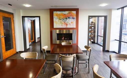 A dining room with a fireplace and chairs.