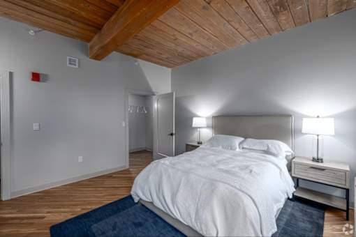 A bedroom with a white bed and a wooden ceiling.