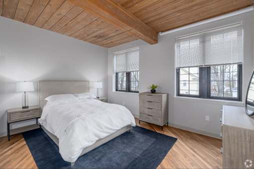 A bedroom with a bed, nightstand, and window.