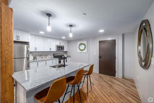 A kitchen with a white countertop and wooden chairs.