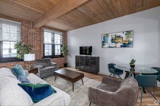 A living room with a grey couch and a wooden ceiling.