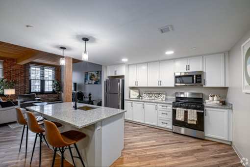 A kitchen with white cabinets and a wooden floor.