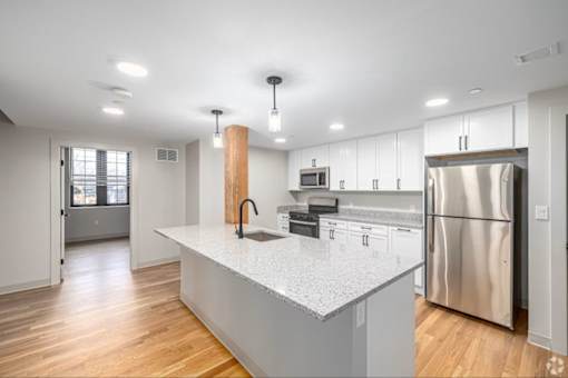 A modern kitchen with a white countertop and stainless steel appliances.