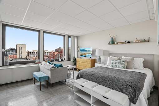A bedroom with a large bed and a window overlooking a cityscape.