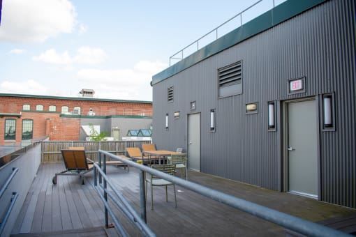the deck of a building with a table and chairs on it
