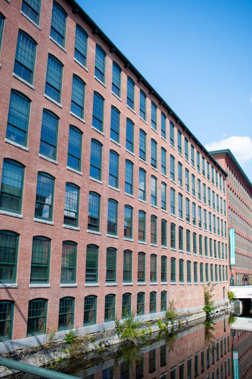 a large brick building with many windows and a river in front