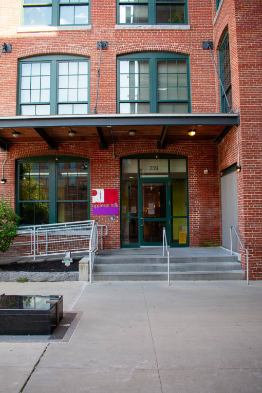 the front of a brick building with a green door and stairs