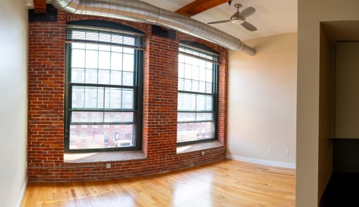 a living room with two large windows and a wood floor