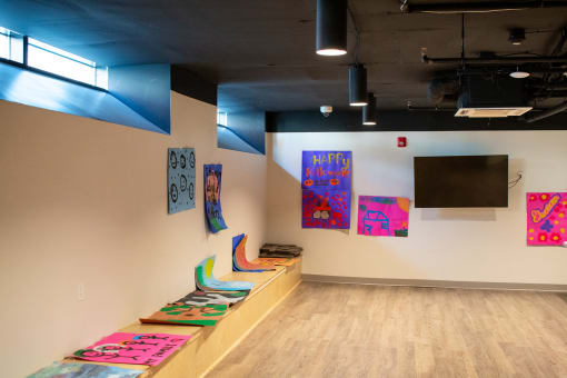 a gallery with paintings on the wall and a row of chairs on the floor