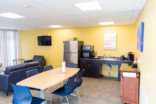 A conference room with a table, chairs, and a television.