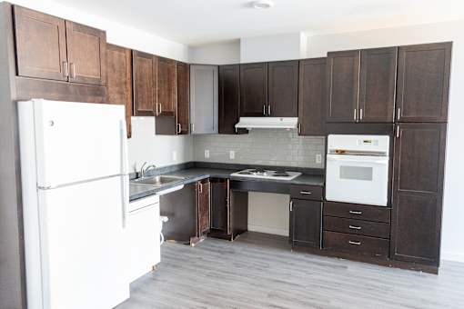 A kitchen with a white fridge and brown cabinets.
