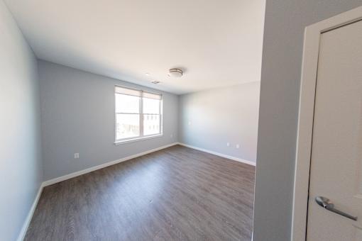 A room with a window and a wooden floor.