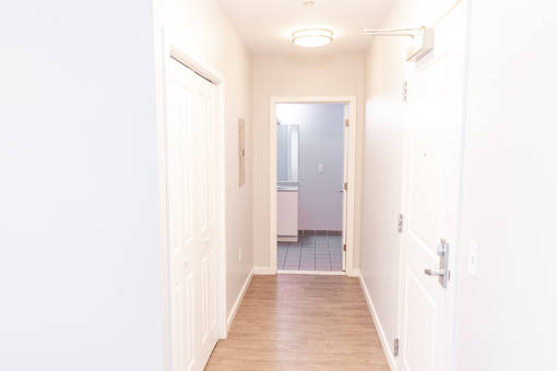 A hallway with white walls and a wooden floor.