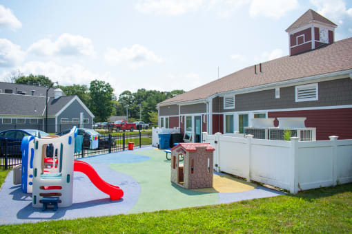 a playground with a slide and other play equipment in front of a house