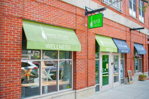 a brick building with a green awning and a sign that says back to life wellness