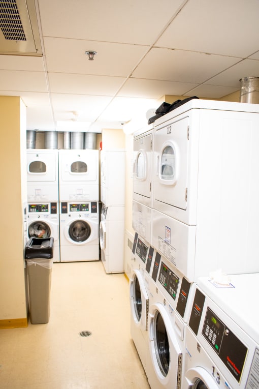 a laundry room with washers and dryers and a trash can