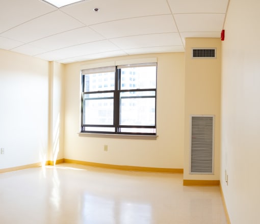 an empty room with a window and a radiator in it