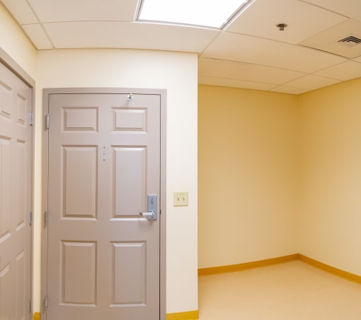 an empty room with a white door and a window