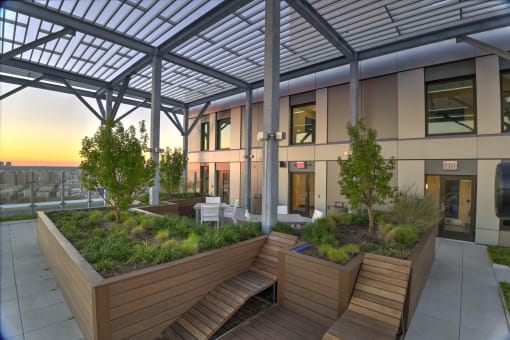 a building with a roof terrace with benches and plants