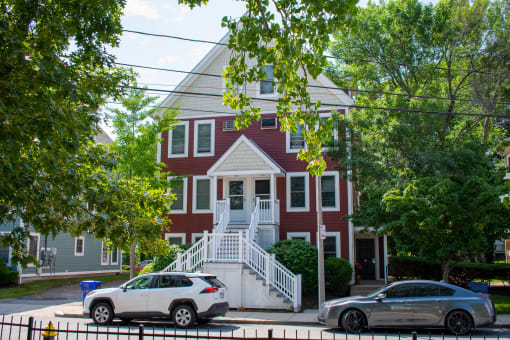 a red and white house with two cars parked in front of it
