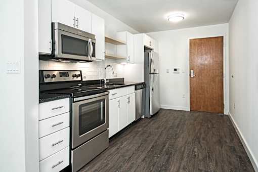 A kitchen with white cabinets and a wooden door.