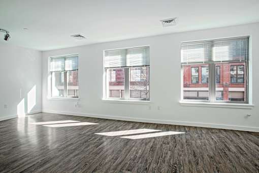 A room with three windows and wooden floors.