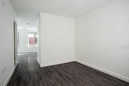 A room with white walls and dark wood flooring.