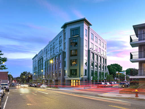 A modern building with a green and white facade stands on a street corner.