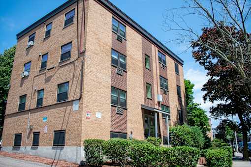 a large brick building with bushes in front of it