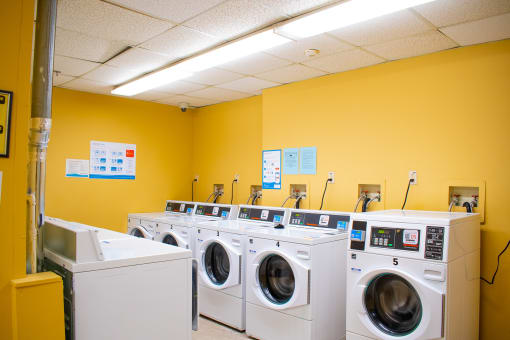 a laundromat with a yellow wall and white washers and dryers