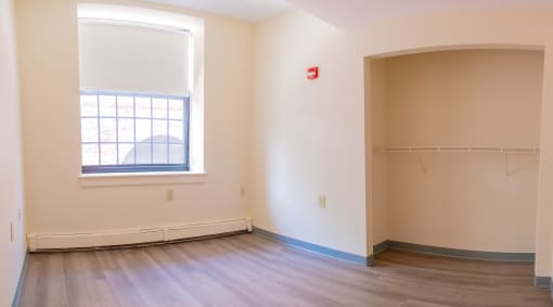 an empty room with wood floors and a large window