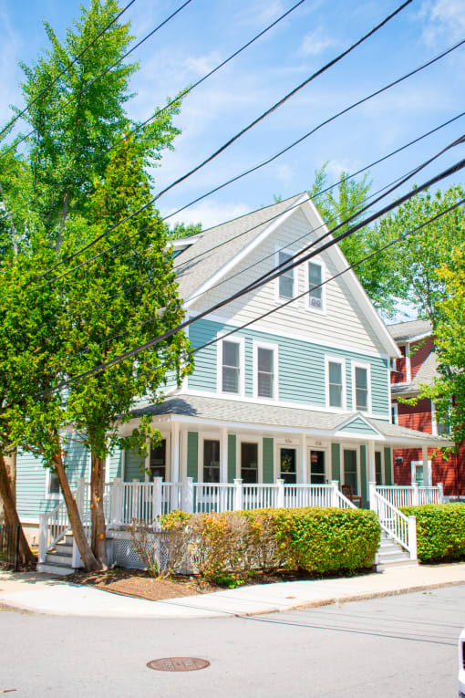 a blue house with a gray roof and a white porch