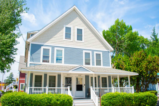a blue house with a white porch and blue siding