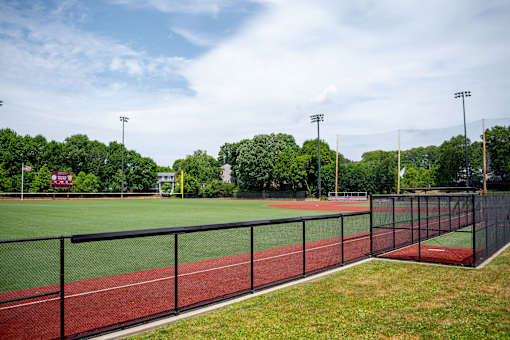 A track and field with a red track and a black fence.