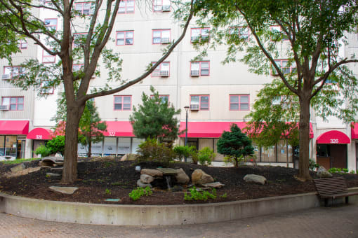 a park with trees and rocks in front of a building