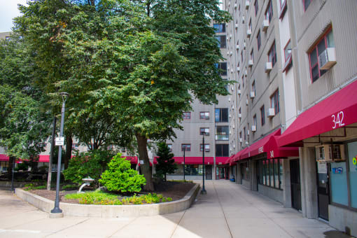 a courtyard with trees and flowers in front of an apartment building