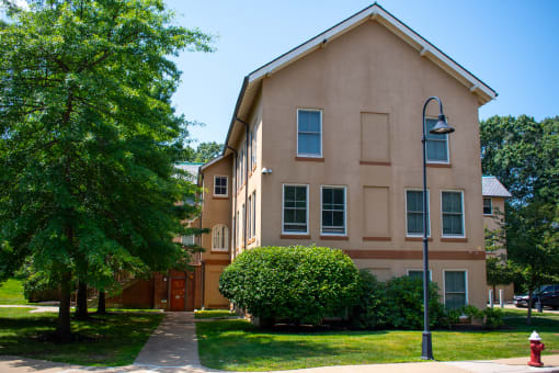 an apartment building with a sidewalk and trees in front of it
