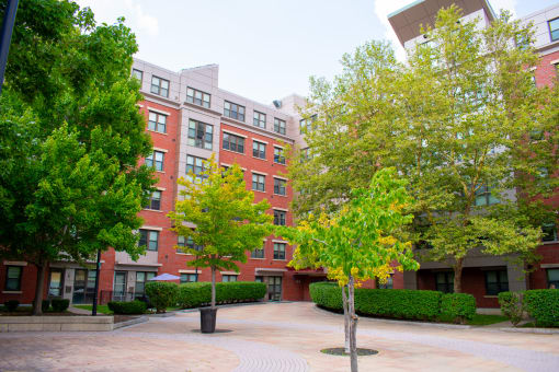 a courtyard with trees and a red brick building in the background