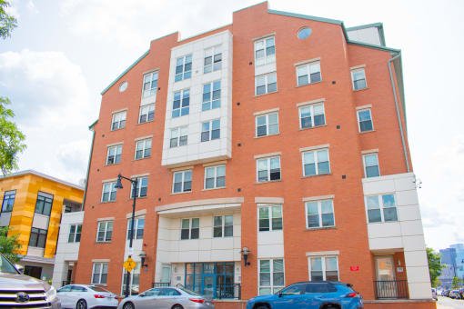 a red brick apartment building with cars parked in front of it