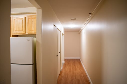 a hallway with a refrigerator and cabinets in a house