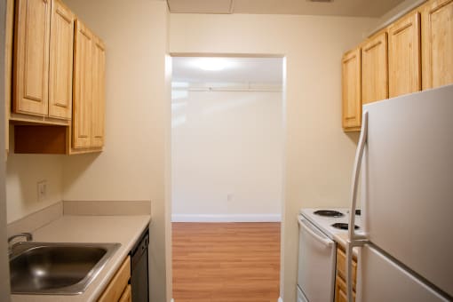 a kitchen with white appliances and wood flooring and a door to the laundry room