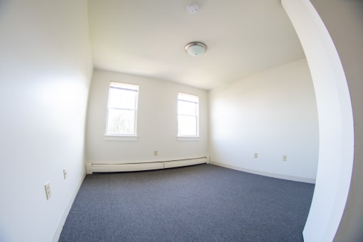 an empty room with white walls and two windows